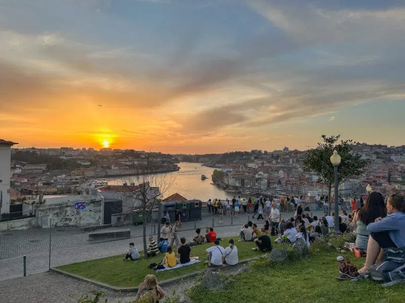 Crowds gathered on the grass to watch the sunset over Porto from Jardim do Morro