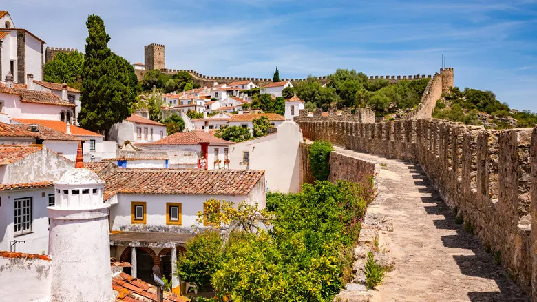 Whitewashed houses with blue and yellow trim enclosed within the medieval stone walls of Óbidos