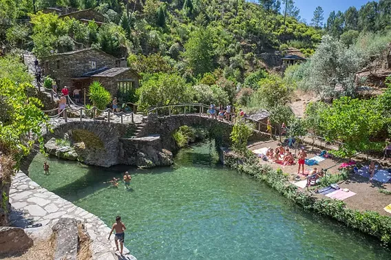 A peaceful praia fluvial river beach with clear water and a sandy bank in central Portugal