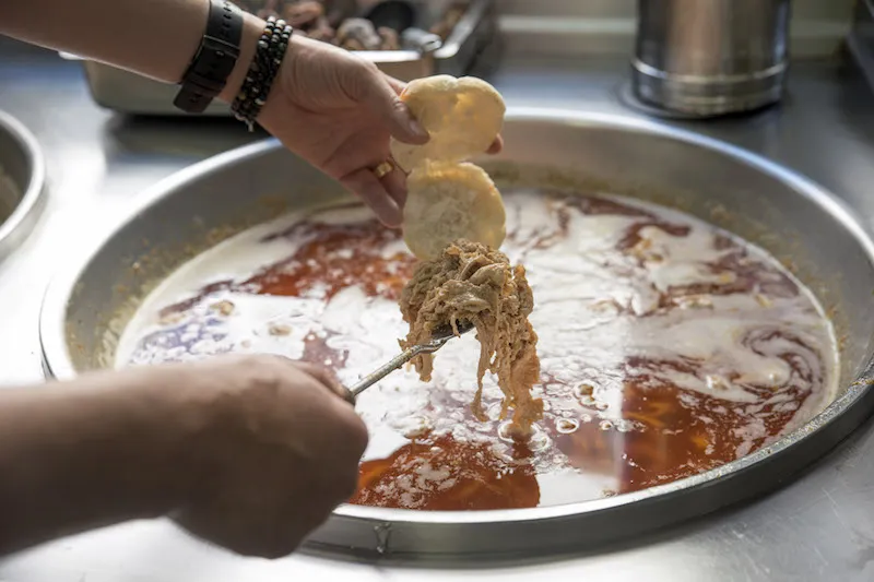 A juicy Porto style bifana dripping with spicy sauce inside a soft roll