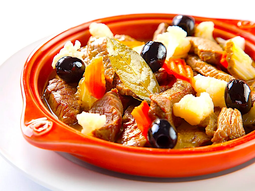 Sizzling pan of pica pau beef with pickles and olives