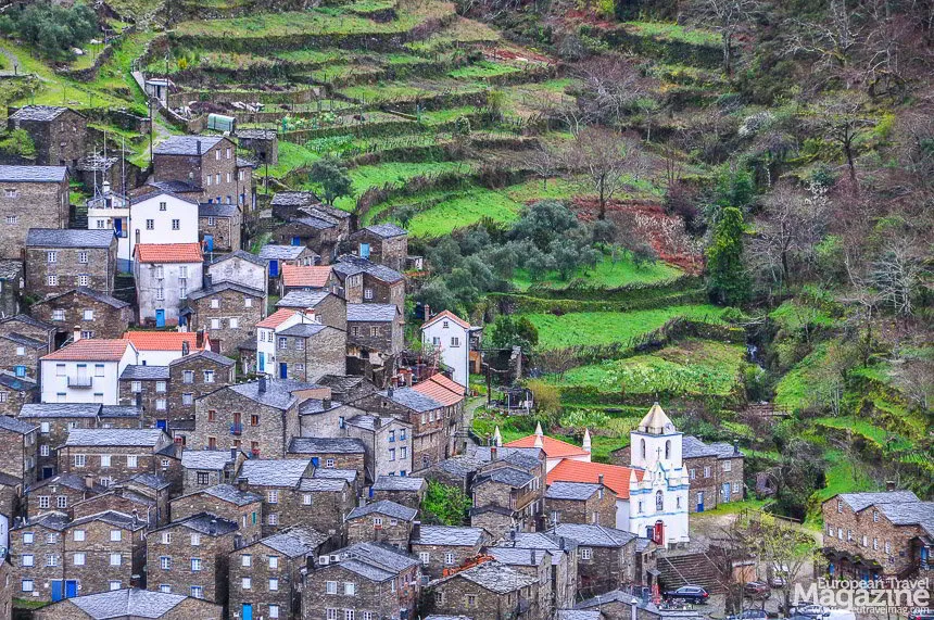 The dark stone houses and blue doors of Piódão cascading down the steep mountain hillside