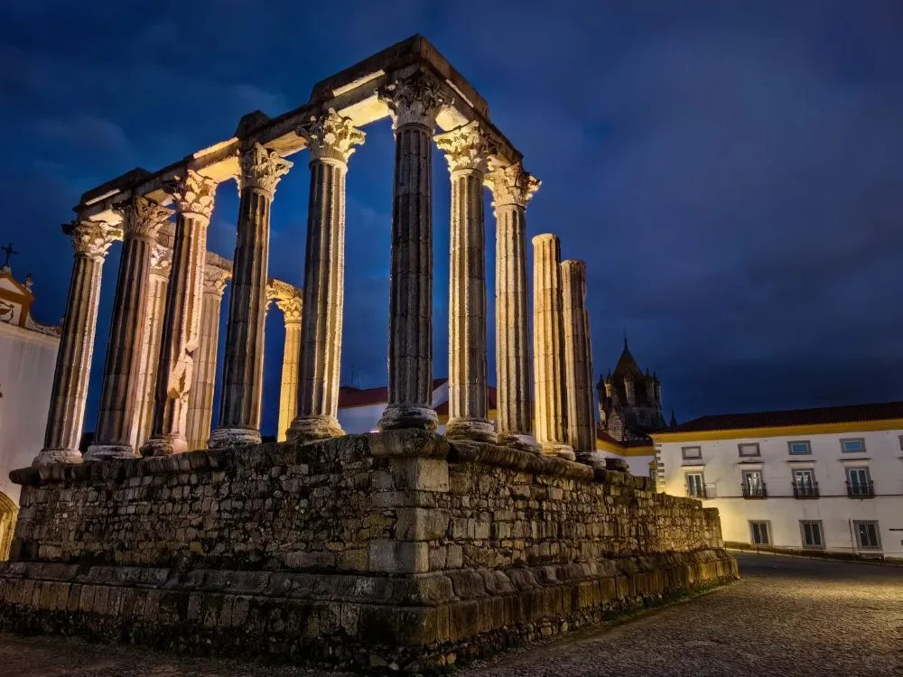 The ancient Roman Temple of Évora dramatically illuminated against the night sky
