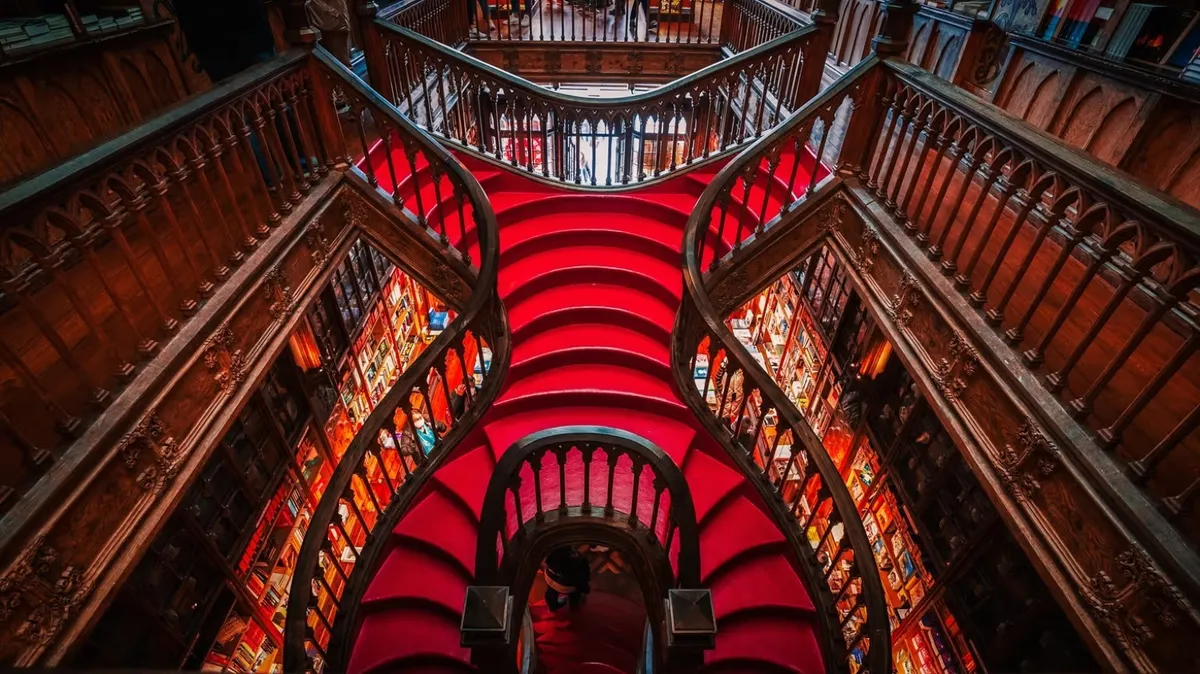 The famous ornate red wooden staircase inside the historic Livraria Lello bookstore