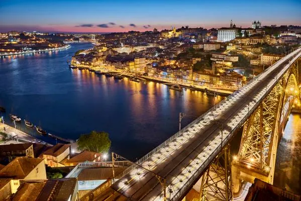 Pedestrians walking on the top deck of the Dom Luís I bridge at sunset